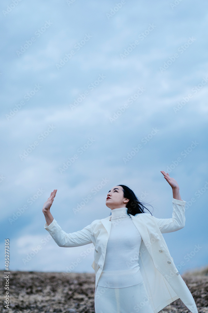 Thoughtful woman standing with hand raised against sky Thoughtful woman standing with hand raised against sky