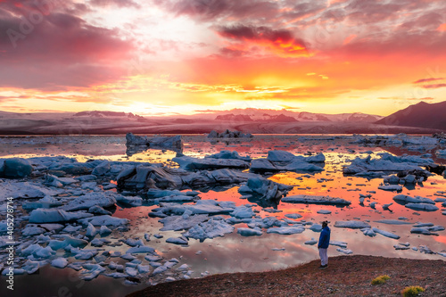 Man looking a sunset in a frozen lake with icebergs in Iceland © Gus