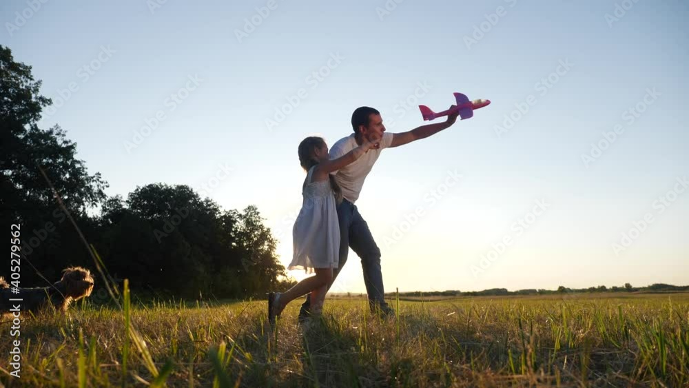 dad and daughter play with a toy airplane in the park in nature with a dog. kid dream concept happy family. dad and daughter play outdoors in the park. happy family dog with dream airplane in nature dad and daughter play with a toy airplane in the park in nature with a dog. kid dream concept happy family. dad and daughter play outdoors in the park. happy family dog with dream airplane in nature