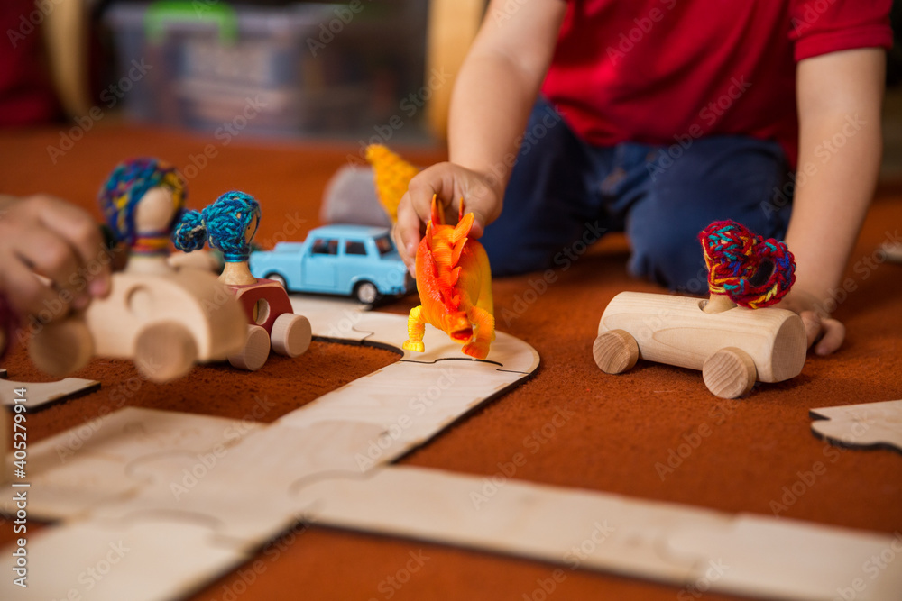 Hands of a child playing with wooden toys at home. Colorful interior of a children's room.