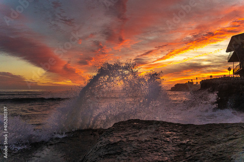 sunset over the sea and a wave smashing on the rock