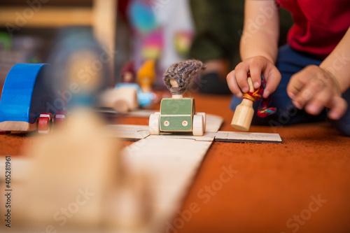 Hands of a child playing with wooden toys at home. Colorful interior of a children's room.