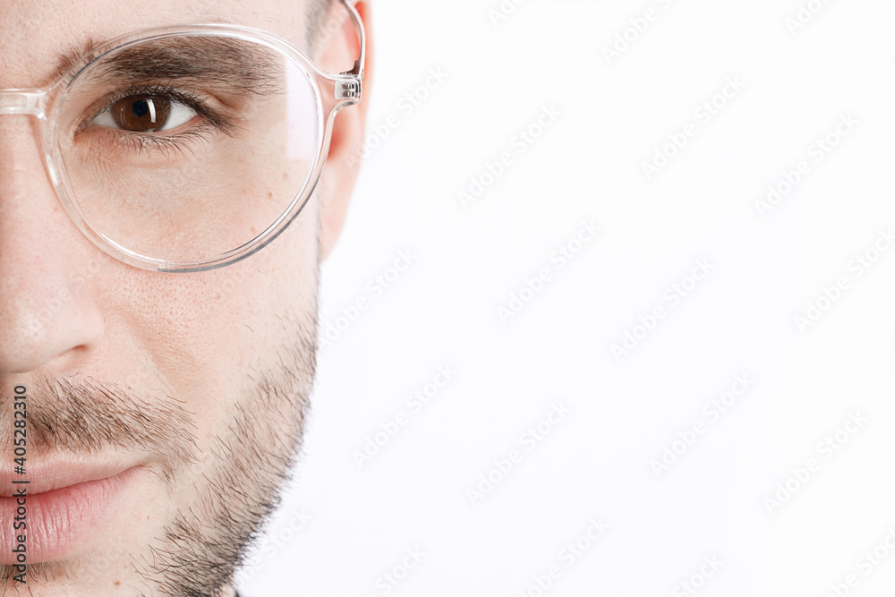 Close up view of brown male eye in glasses. White background. Portrait of beautiful man.