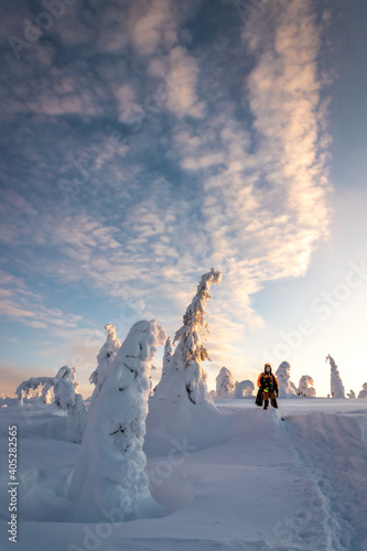 Man doing trekking on a snowy hill on a sunset with some clouds © Gus