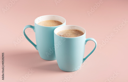 Two light blue mugs with coffee stand on a powdery background, horizontal orientation