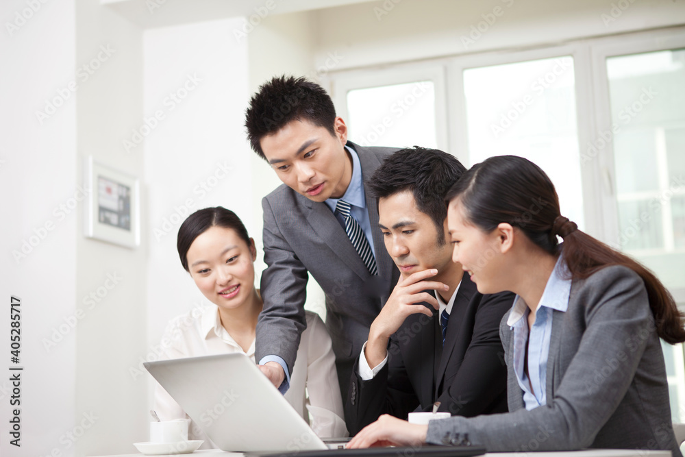 Group of businesspeople discussing working on computer Group of businesspeople discussing working on computer