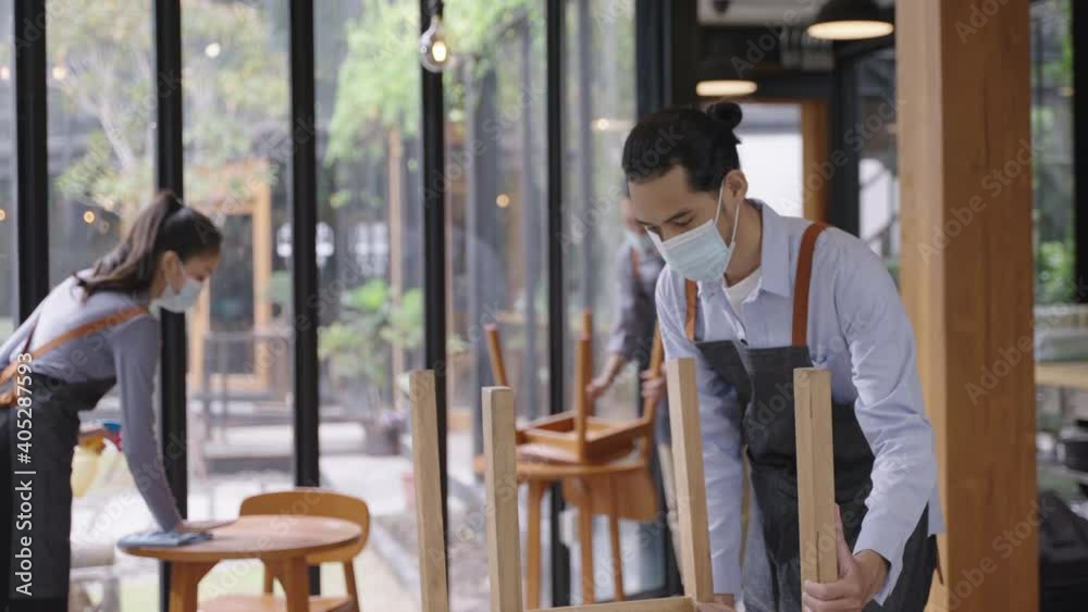 Group of Asian restaurant staff in apron wearing face mask, cleaning and arranging the table with social distancing concept, preparing for reopen after lockdown due to coronavirus pandemic. Group of Asian restaurant staff in apron wearing face mask, cleaning and arranging the table with social distancing concept, preparing for reopen after lockdown due to coronavirus pandemic.
