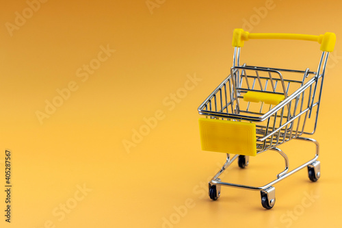 Bsmall shopping cart on yellow background, copy space, shopping concept