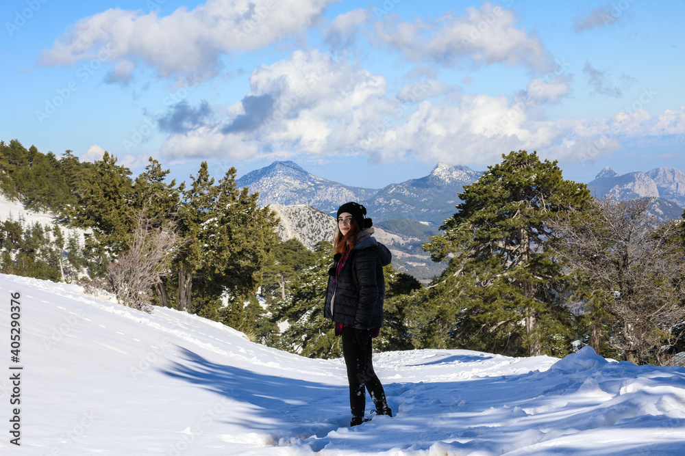 Selective focus of young woman on snow against a beautiful mountain and blue cloudy sky, Winter Concept Landscape.
