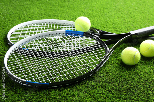 Tennis rackets and balls on green grass. Sports equipment © New Africa