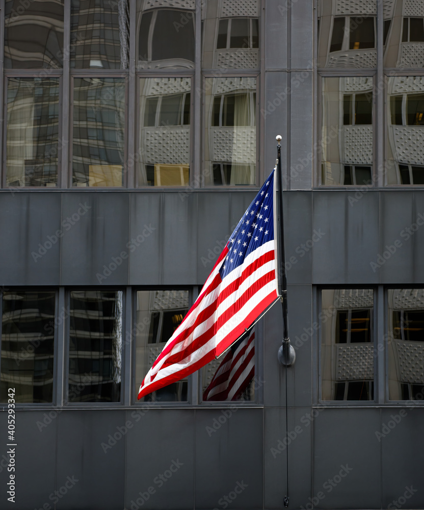 Fototapeta premium American flag hanging on a dark building with reflections.