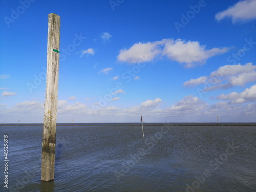 Holzpfähle markieren die Fahrrinne an der Einfahrt zum Hafen von Bensersiel bei Esens an der Küste der Nordsee in Ostfriesland in Niedersachsen photo