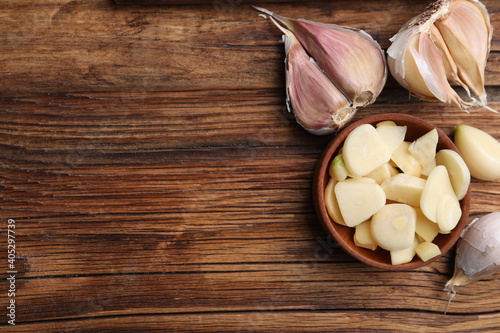 Fresh organic garlic on wooden table, flat lay. Space for text