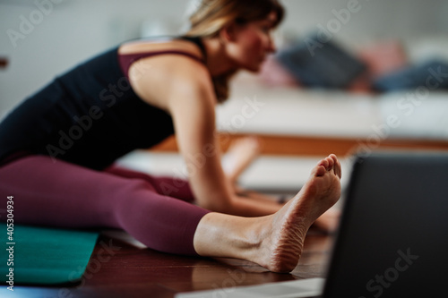 Woman practicing yoga at home with video tutorial.