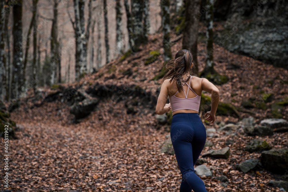 Young sportswoman running in forest during autumn at Ordesa National Park, Huesca, Spain Young sportswoman running in forest during autumn at Ordesa National Park, Huesca, Spain