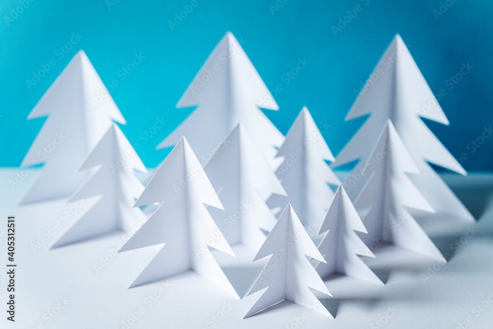 Paper forest with white trees on table against blue background