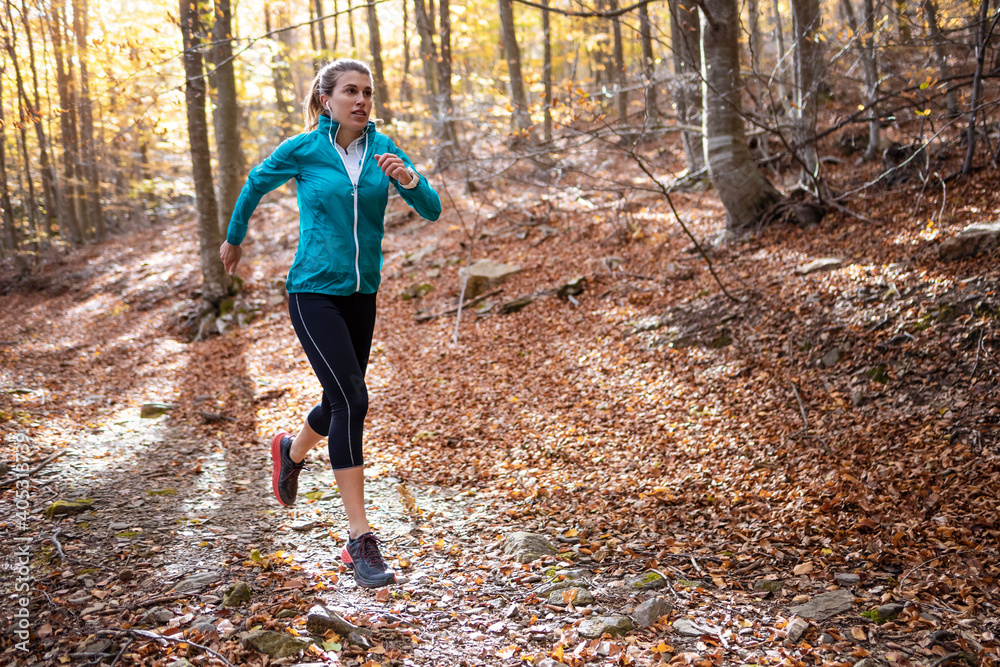 Young sportswoman practicing while running on forest path Young sportswoman practicing while running on forest path