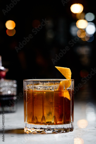 Canvas-taulu Closeup glass of godfather cocktail with slice of orange and ice cubes at bright bar background