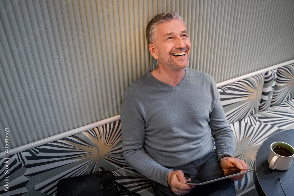 © Floco Images/Westend61 - Happy businessman with digital tablet looking up while sitting at modern cafe © Floco Images/Westend61 - Happy businessman with digital tablet looking up while sitting at modern cafe