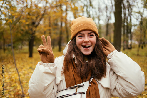 Beautiful woman doing peace sign while standing in autumn park