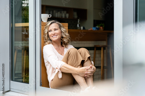 Female entrepreneur day dreaming while sitting at doorway of office cafeteria