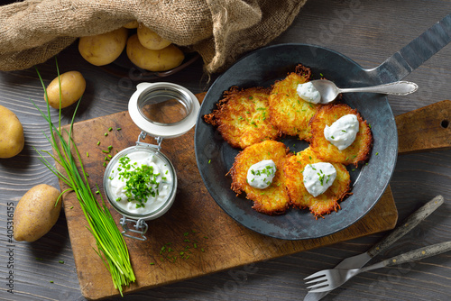 Resche bayerische Kartoffelpuffer mit Schnittlauchquark in der Eisenpfanne serviert – Crunchy Bavarian potato pancakes with sour cream and fresh chives 