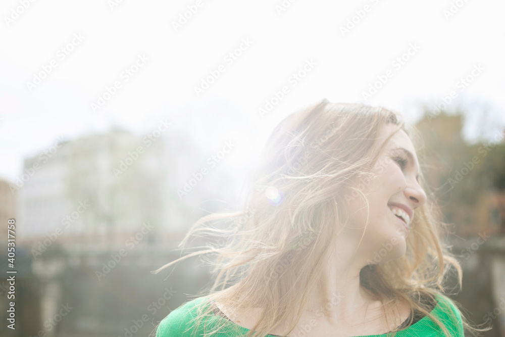Portrait of young woman, shaking hair in sunlight