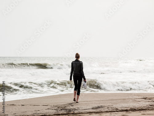 Rear view of mid adult woman strolling on beach, Torreblanca, Andalucia, Spain photo