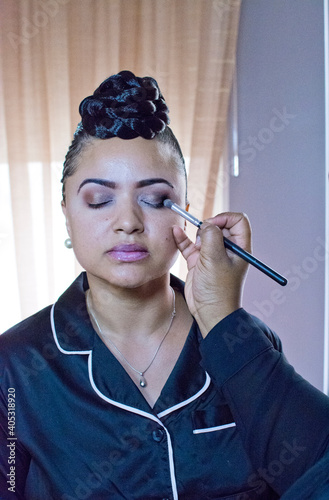 Bride having eyeshadow applied in hotel room