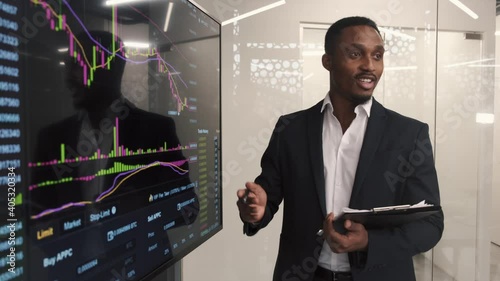 Trading stocks online. Businessman working in office standing at screen, discussing and checking global currency index on fund exchange.