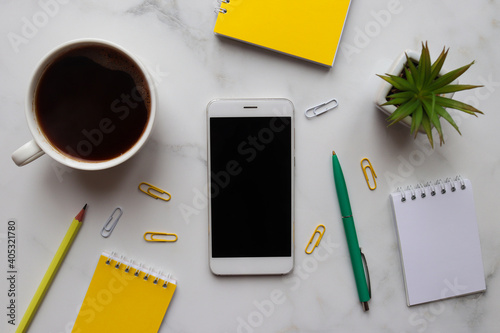 Workspace organization. Morning concept, start of work. Trendy workplace with notepads, smartphone, coffee, pencil, pen, and succulent plant on marble background. Top view, flat lay