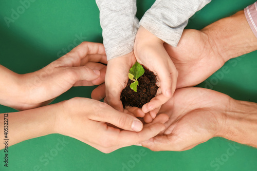 Hands of family with soil a...