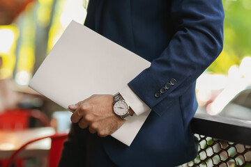 Young businessman with blank magazine outdoors