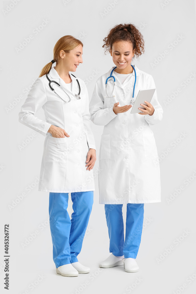 Portrait of female doctors with tablet computer on light background Portrait of female doctors with tablet computer on light background