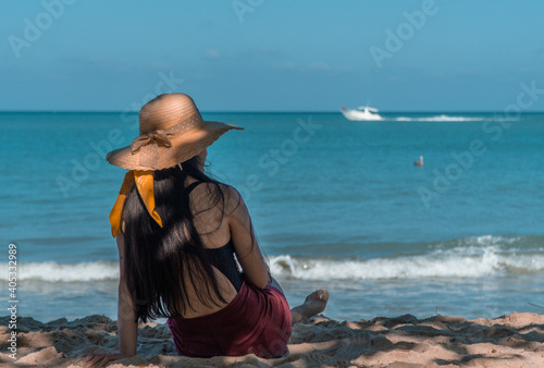 Mujer en la playa sentada frente al mar azul 