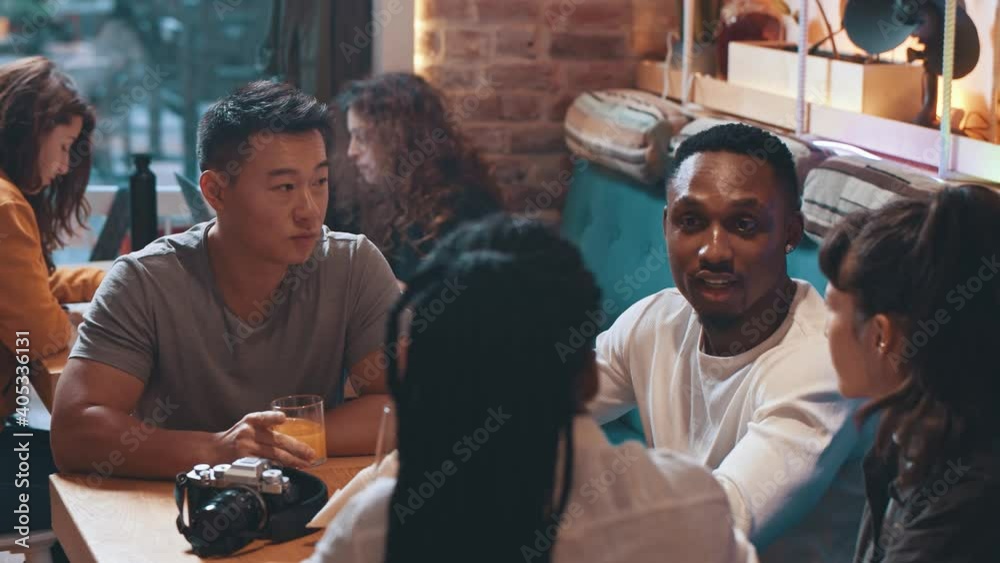 Young multi ethnic group of friends talking and discussing. People discussing interesting news hangout, diverse millennial students hanging in cafe together while having fun conversation and laughing