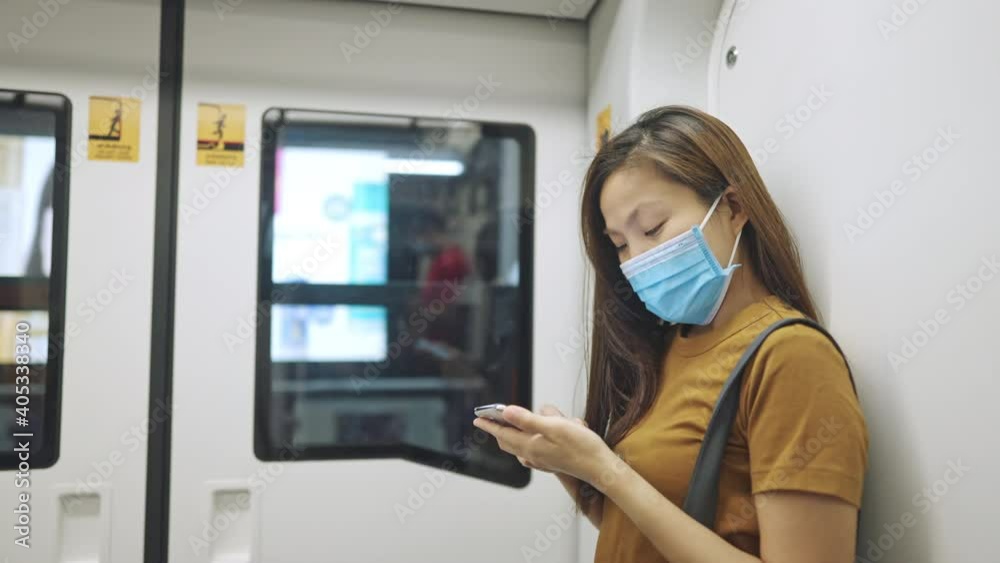 asian woman wearing protective face mask using smartphone on the train asian woman wearing protective face mask using smartphone on the train