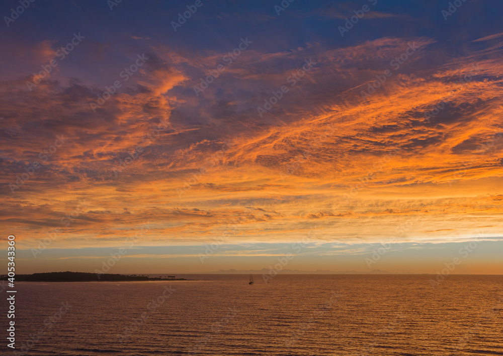 Vista de paisaje de mar y cielo con nubes iluminadas de colores naranja y dorado del atardecer y amanecer 