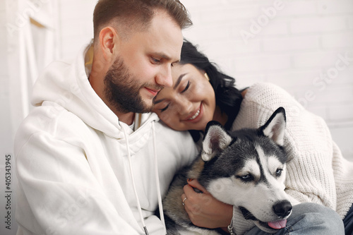 Fototapeta Naklejka Na Ścianę i Meble -  Cute couple in a bedroom. Lady in a white sweater. Pair with a dog