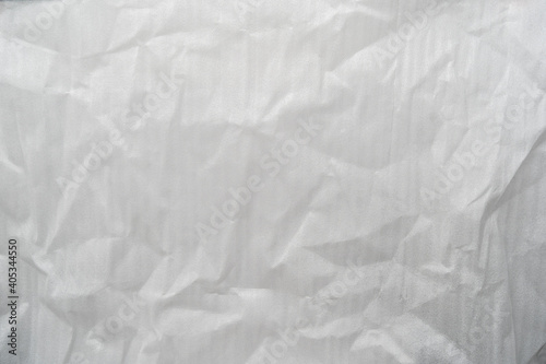 Crumpled white plastic foam foil texture perfect for background structure. Packaging material with rough wrinkles. The grunge textured surface can be used as backdrop.