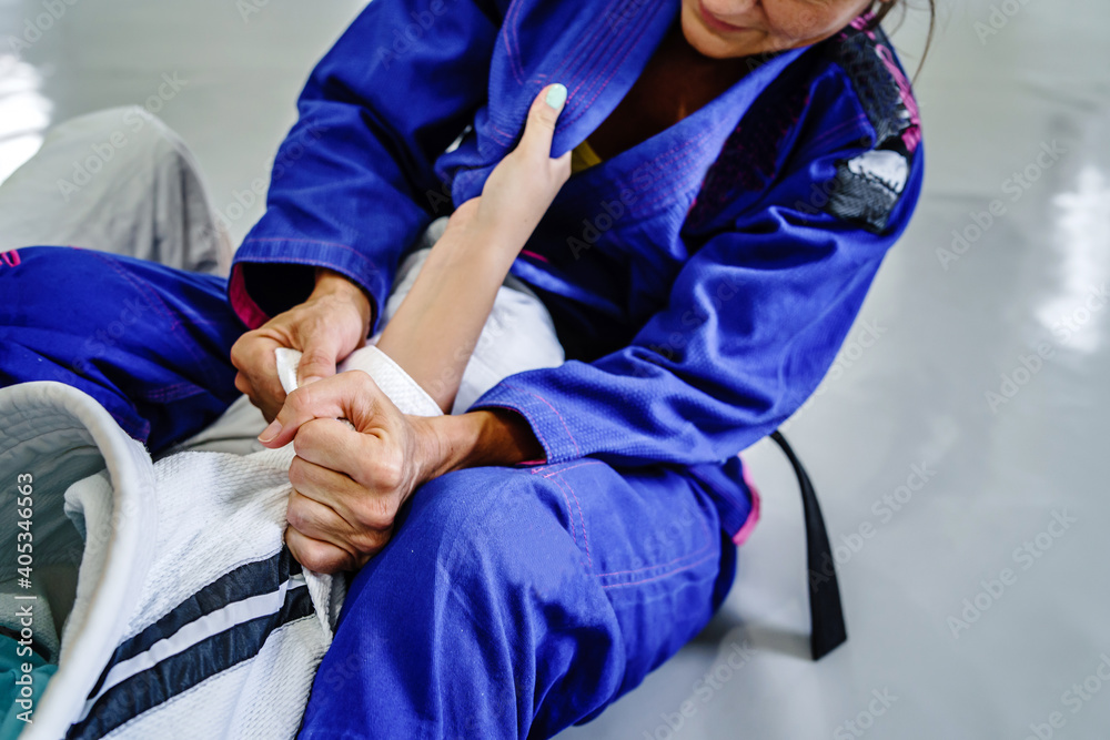 Grips from the guard in brazilian jiu jitsu bjj or judo training sparring  two female women athletes fighters drilling techniques for the competition  advanced guard holding kimono gi for self-defense Photos