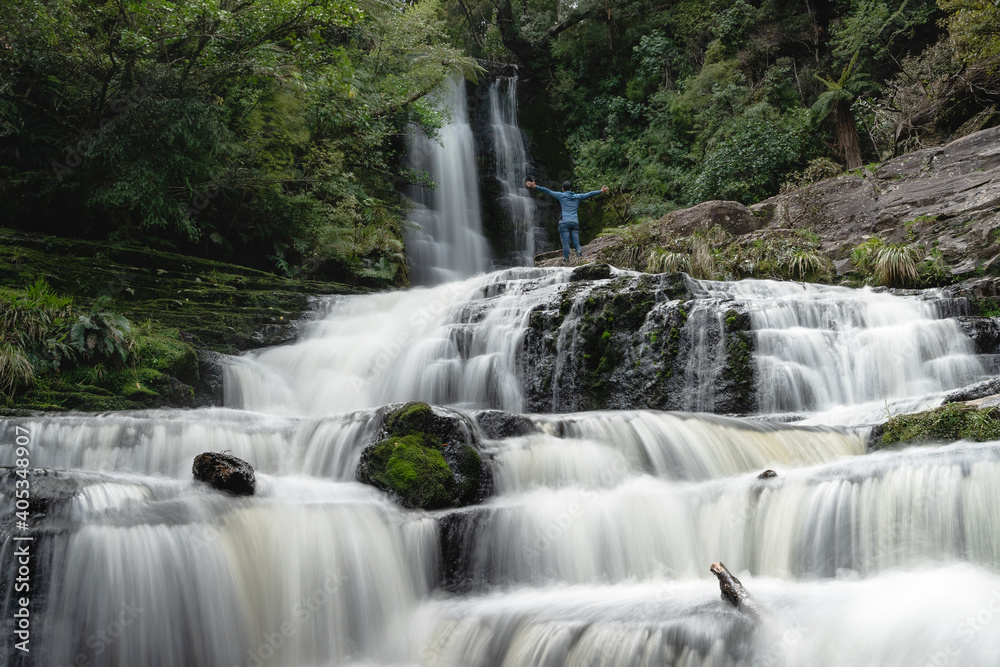 Fototapeta premium Man opening his arms at the majestic McLean falls. New Zealand, South Island