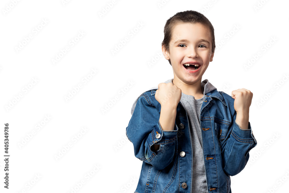 Portrait of a cheerful smiling boy in denim jacket holding fists and rejoicing at his achievements and victory on white isolated background Portrait of a cheerful smiling boy in denim jacket holding fists and rejoicing at his achievements and victory on white isolated background