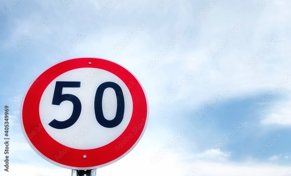 Fifty speed limit traffic sign on a main road with mountain and blue sky background