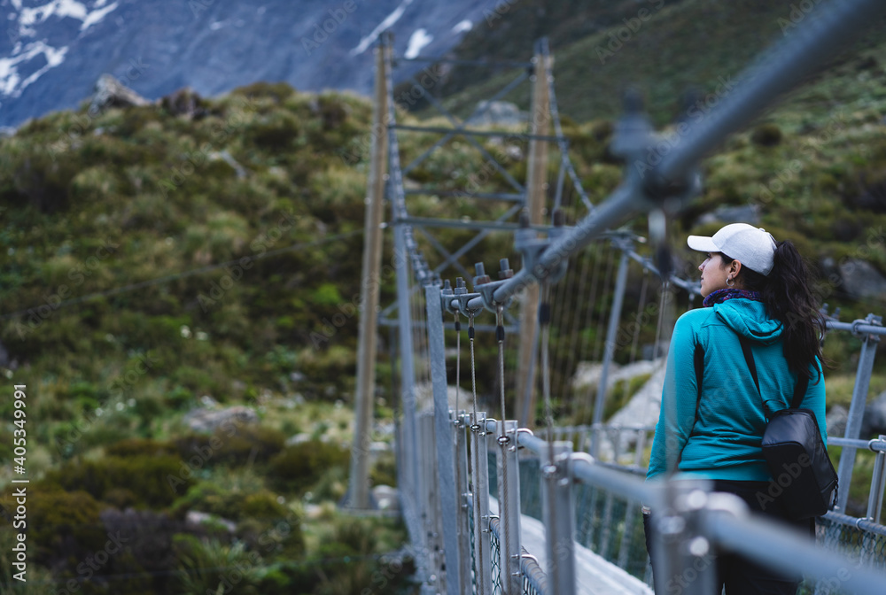 Woman on suspension bridge looking at the landscape in Hooker Valley Track. New Zealand Woman on suspension bridge looking at the landscape in Hooker Valley Track. New Zealand