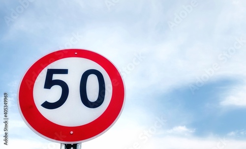 Fifty speed limit traffic sign on a main road with mountain and blue sky background