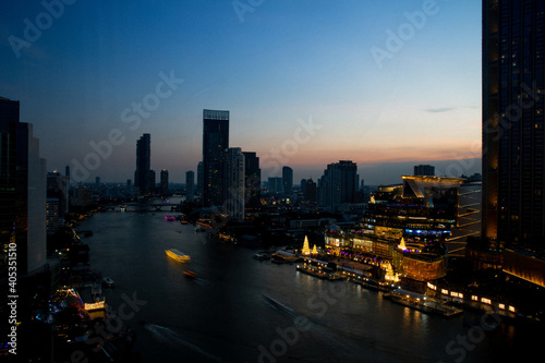 The Chao Phraya River flows through Bangkok in the Sathorn area  with bridges over the river and boats when the sun is setting.