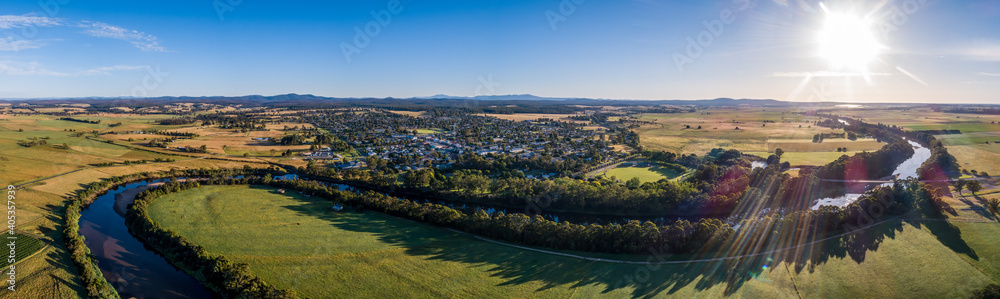 Amazing river bends among green fields and small town in Australian outback at sunset - wide aerial panorama