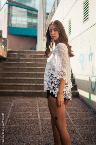Fotografie A shallow focus of an adult female wearing a white lace shirt with shorts and po