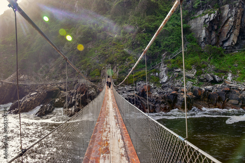 Walking on the suspension bridge over the Storms River Mouth in late afternoon light. Lensflare creates a  unique mood. Tsitsikamma National Park Garden Route South Africa